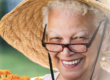 Senior woman with glasses and hat holding marigold plans