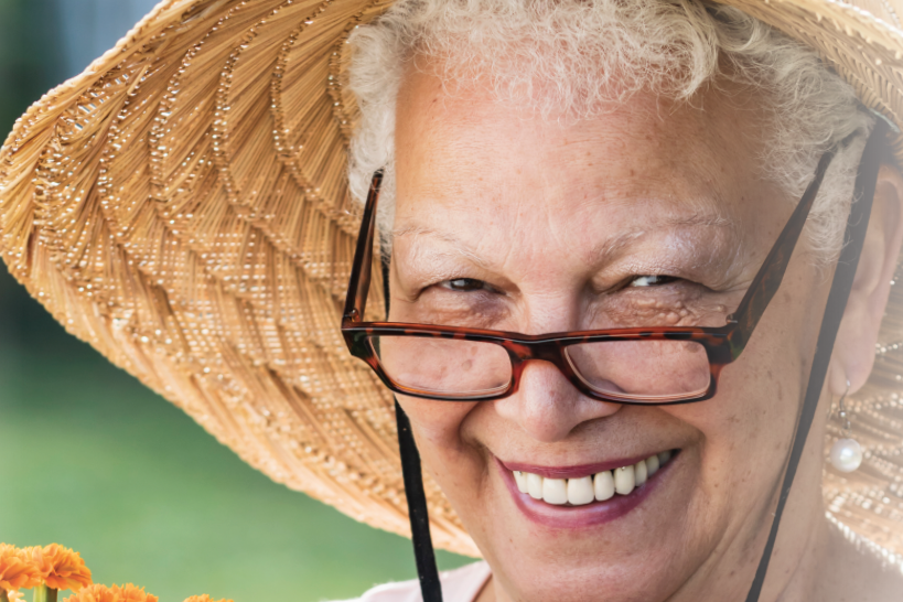 Senior woman with glasses and hat holding marigold plans